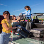 Two women and child unloading luggage from car.