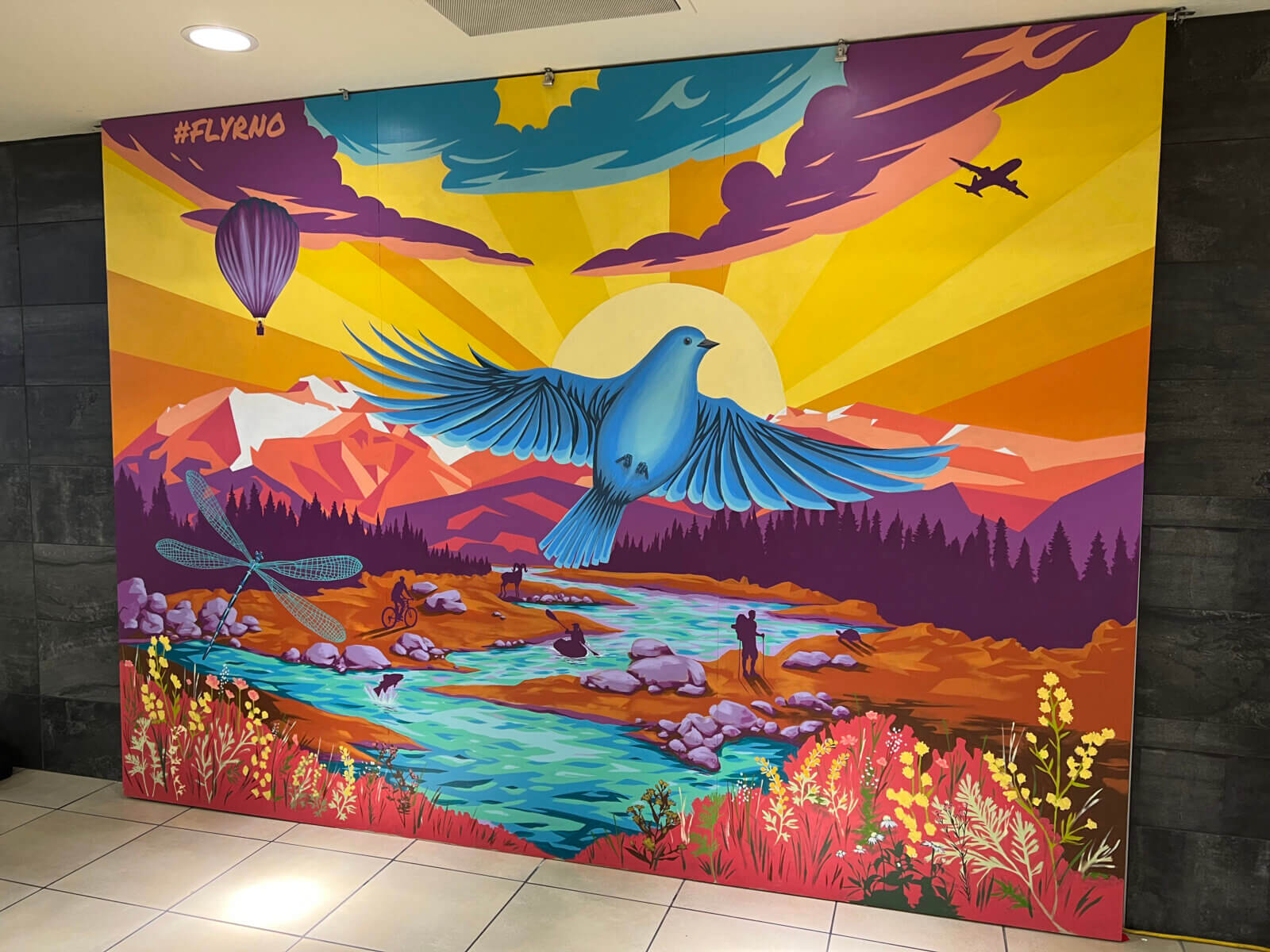 RNO colorful interactive mural depicting Reno-Tahoe area, native wildlife, and people enjoying outdoor activities.