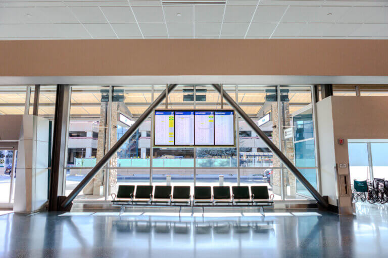 Front view of Arrivals and Departures screens with brown chairs in the Ticketing Hall.