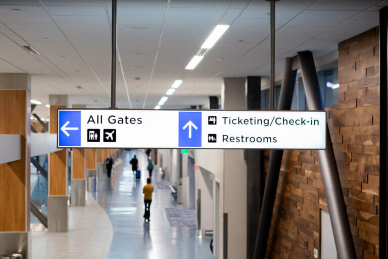 Ticketing Hall directional signage reading "All Gates", "Ticketing/Check-in", and "Restrooms".