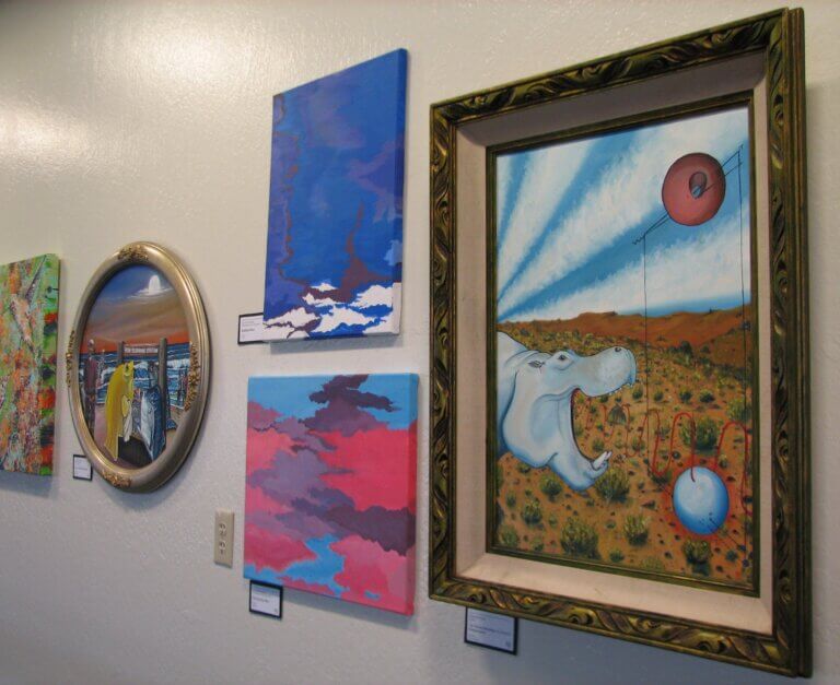 First Annual Employee Art Show Exhibition wall featuring several paintings.