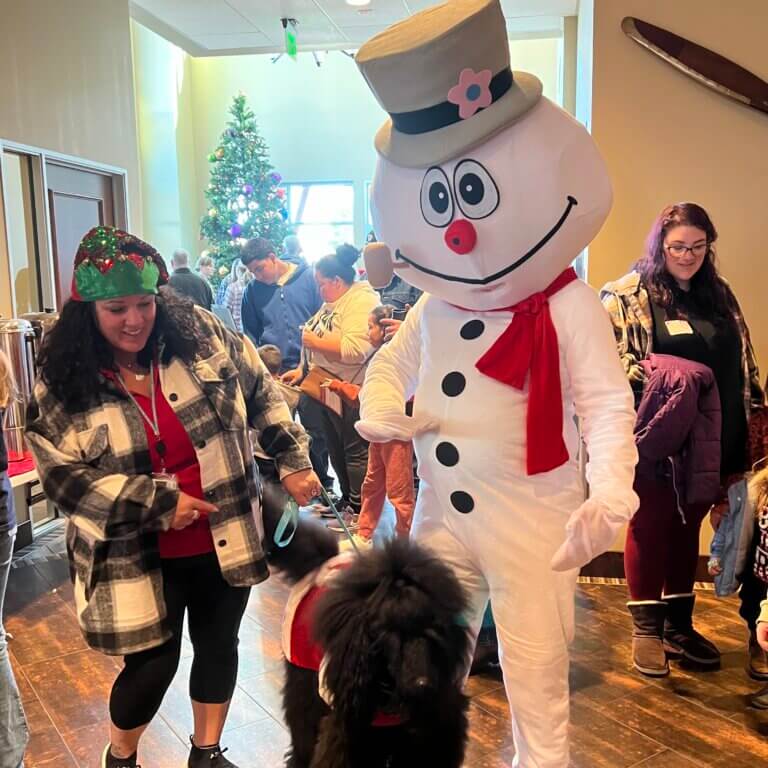 Person wearing a Frosty the Snowman costume near a dog and children