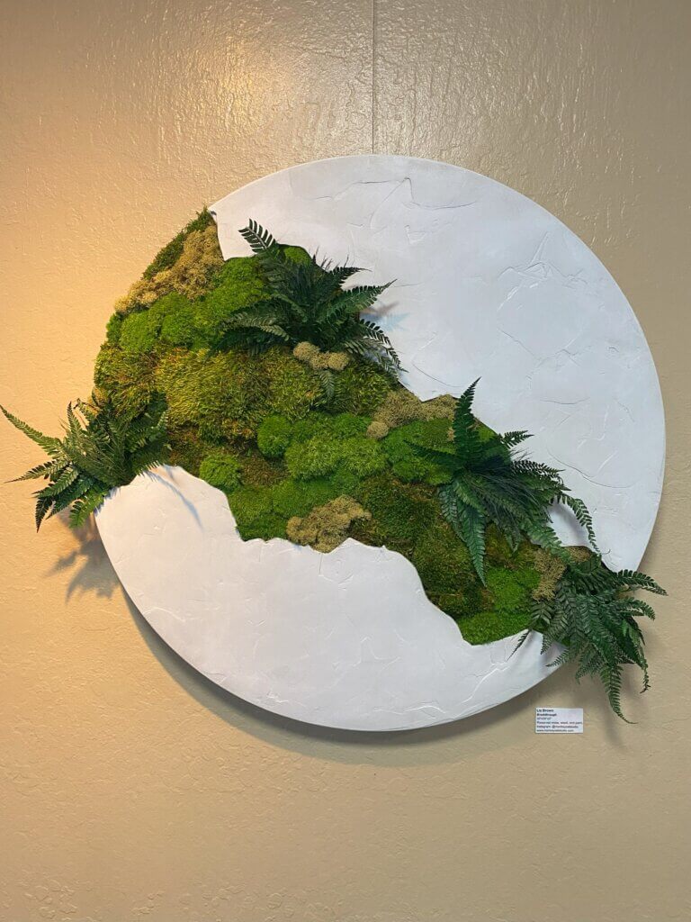 Artwork with greenery cutting through a white circle.