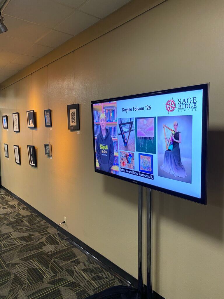 Gallery wall and TV playing Sage Ridge student video.