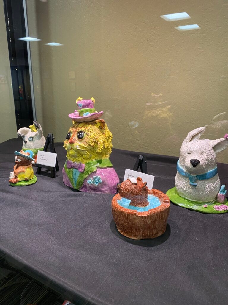 Various clay animals, including a dog and a cat, inside a display case.