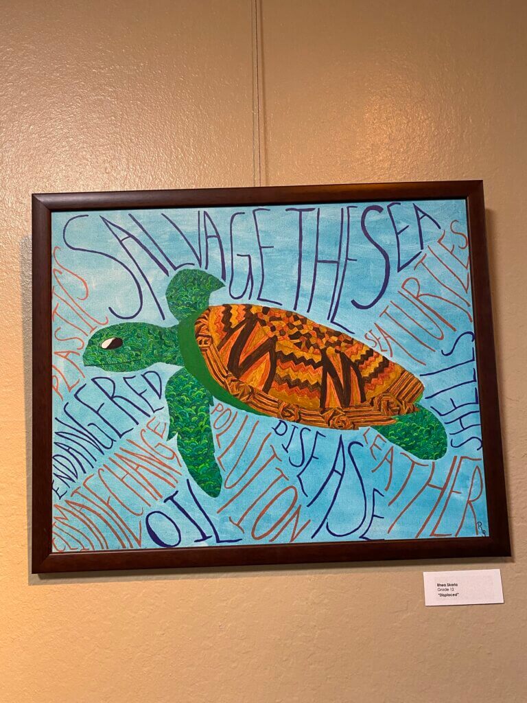 Painting of a turtle with various words throughout including "salvage the sea" and "climate change".